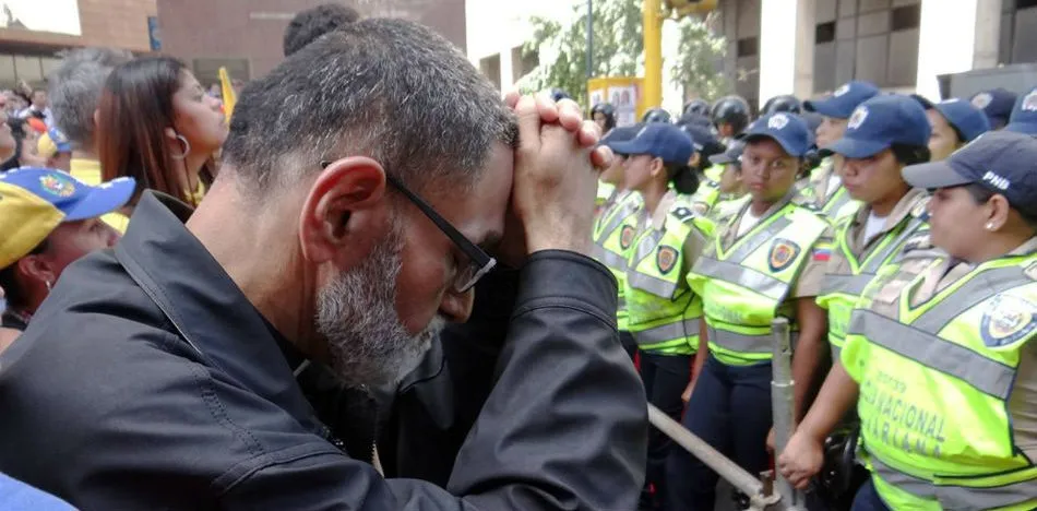 Padre José Palmar orando frente a la policía en una protesta pacífica